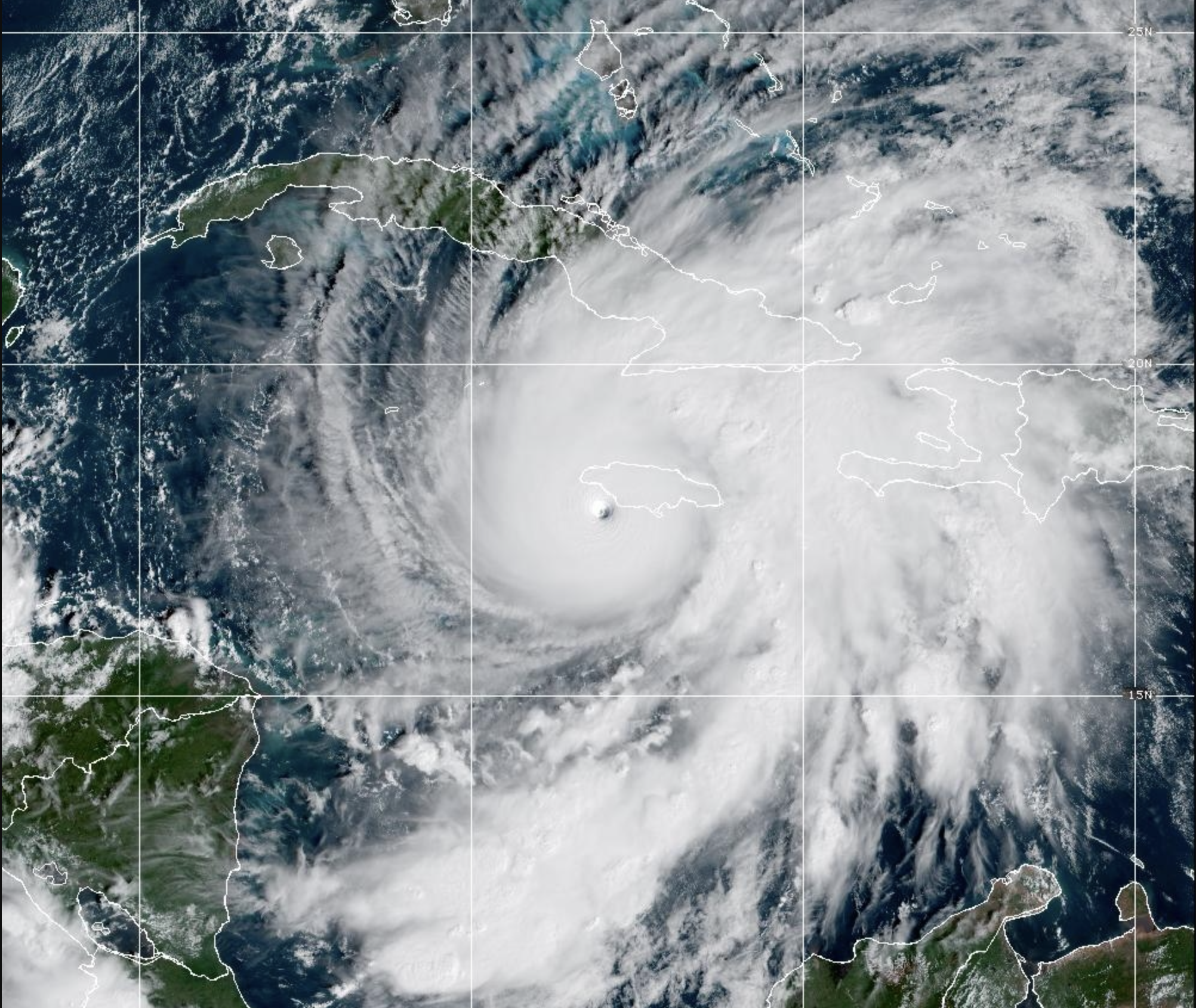 GOES-19 satellite imagery showing Hurricane Melissa as a powerful Category 5 storm with a clearly visible eye preparing to make landfall on Jamaica's southwestern coast. The massive hurricane dominates the frame with bright white cloud bands spiraling outward, while Jamaica's green landmass is outlined in white at the top left, directly in the storm's path. Haiti and other Caribbean islands are also visible with white boundary lines.